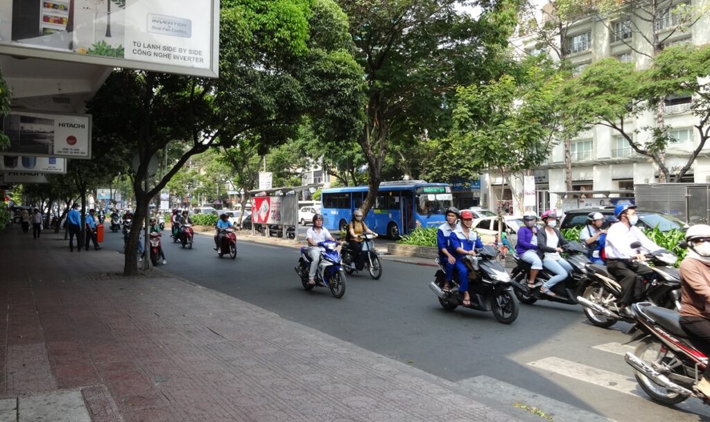 多くのバイクと青い路線バスが行き交うホーチミン市内の街並み