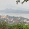 ルアンパバーンの高台から市街地と川、周囲の山々を見渡した風景。手前には伝統的な屋根の建物が密集し、奥には霞に包まれた山並みが続く。
