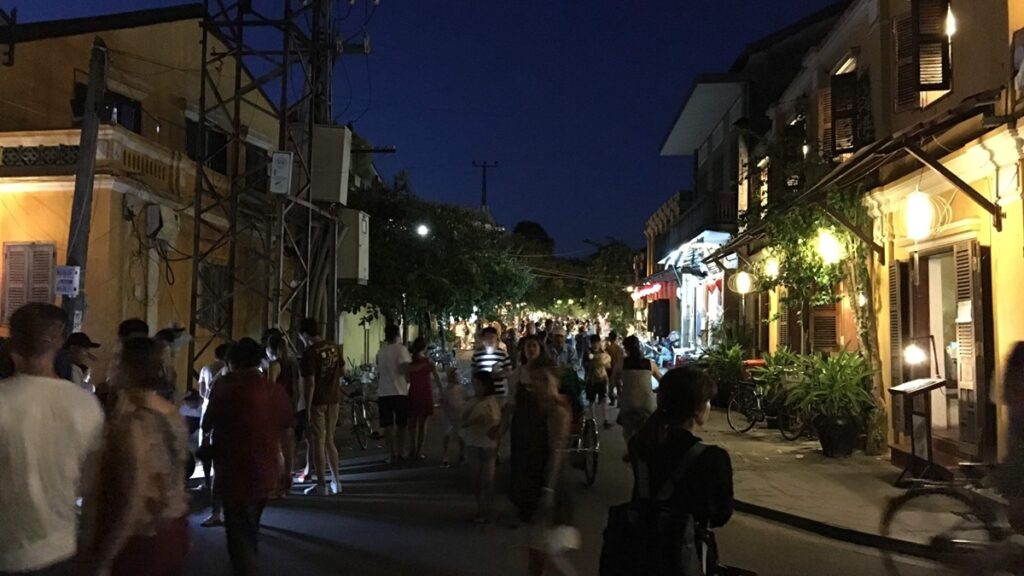 夜のホイアン旧市街で黄色い歴史的建物に明かりが灯り、多くの観光客が散策する様子