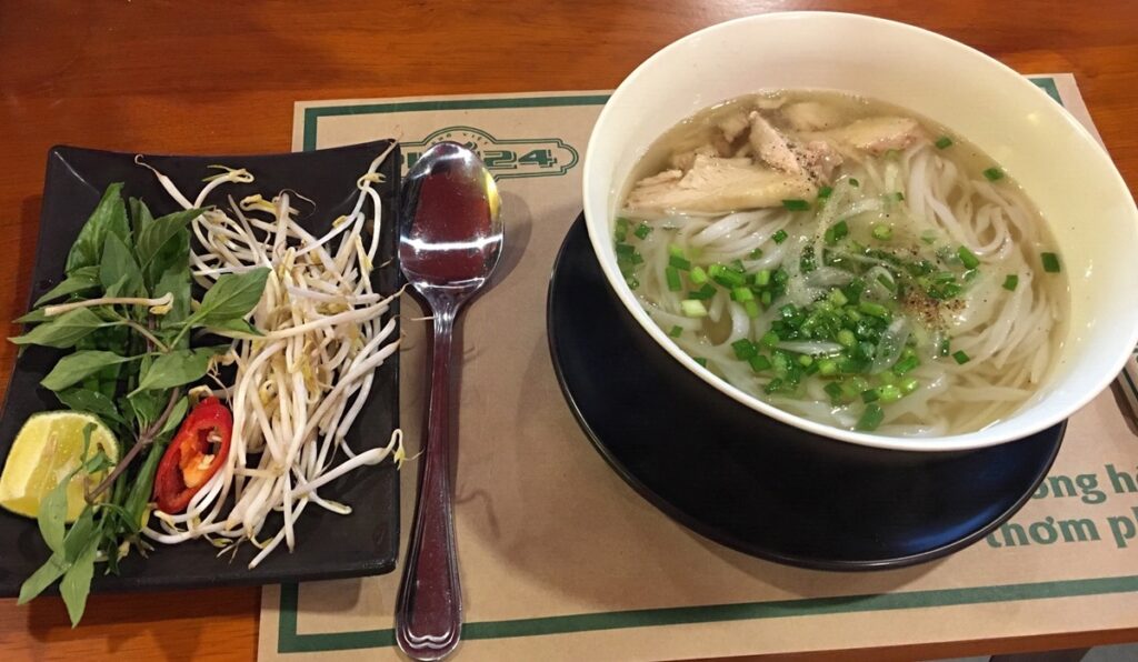 ベトナム料理のフォー。米麺と肉、ネギが入ったスープに、もやし、香草、ライム、唐辛子が添えられている
