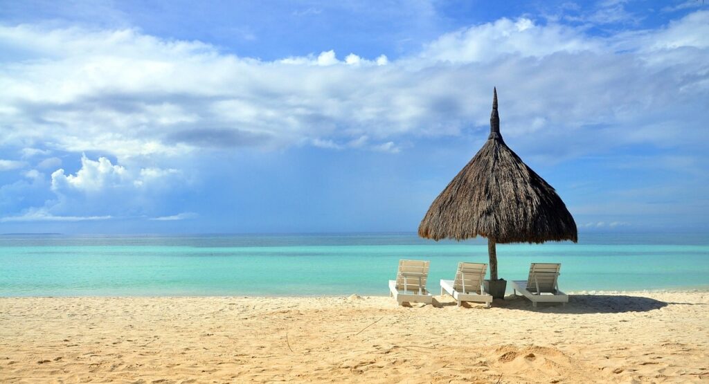 フィリピンの美しいビーチに並ぶパラソルとビーチチェア、エメラルドグリーンの海が広がる南国リゾートの風景