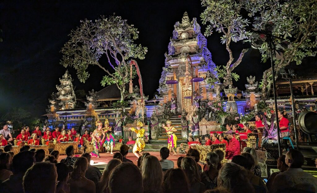 夜の寺院を背景に、華やかな衣装の踊り手とガムラン奏者が並んでいる