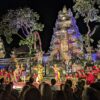 夜の寺院を背景に、華やかな衣装の踊り手とガムラン奏者が並んでいる
