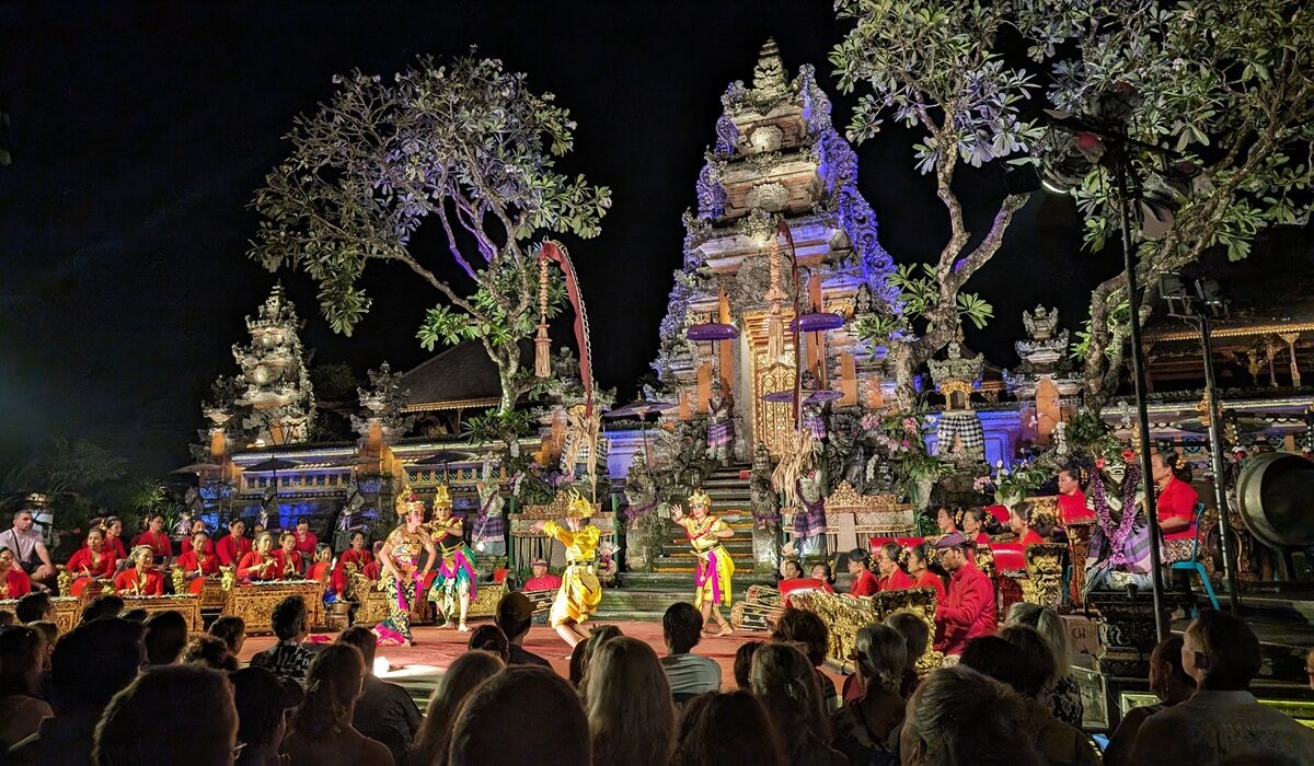 夜の寺院を背景に、華やかな衣装の踊り手とガムラン奏者が並んでいる